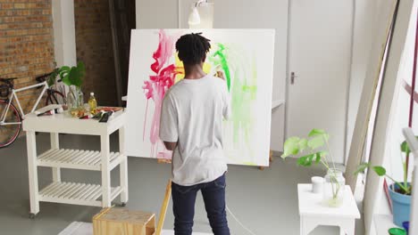 rear view of african american male artist painting on canvas at art studio