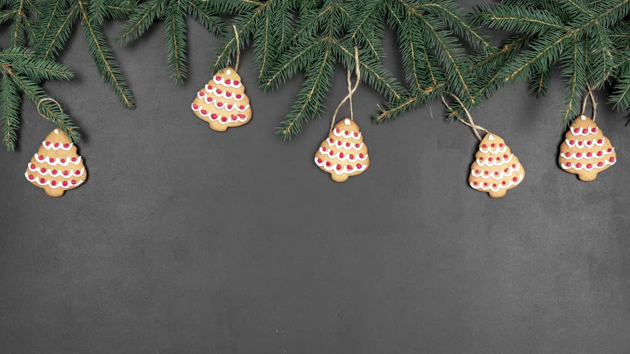 animación de stop motion de bucle sin costuras con ramas de abeto verde como marco y galletas en forma de árbol de navidad en un fondo de pizarra negra. maqueta abstracta con espacio de copia