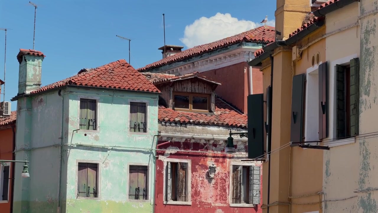 Immagine statica in 4K di case storiche colorate con tetti in terracotta e facciate consumate dal tempo sotto un cielo azzurro e limpido. Tranquillo quartiere urbano in pieno giorno.