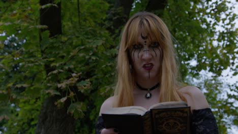 Beautiful Witch smiling in an evil way to the camera and turning around in the cemetery, slow motion Close up