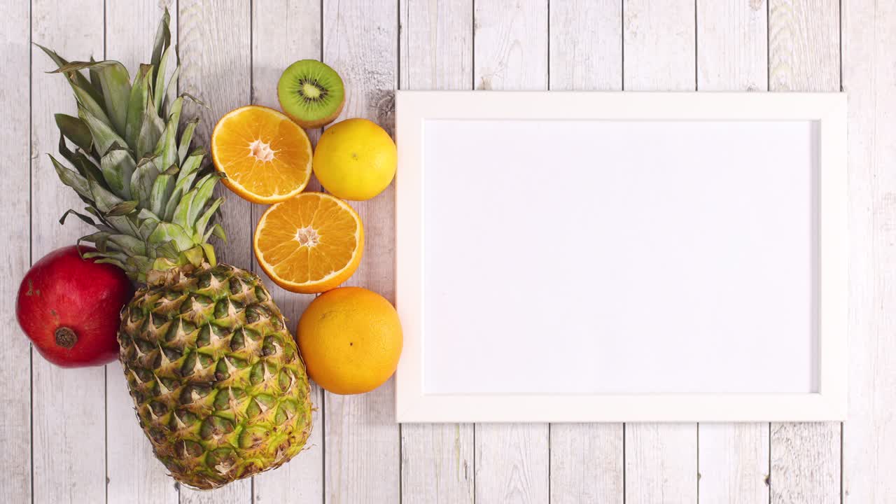 Pineapple, kiwi, orange and pomegranate appear with frame on wooden theme. Stop motion