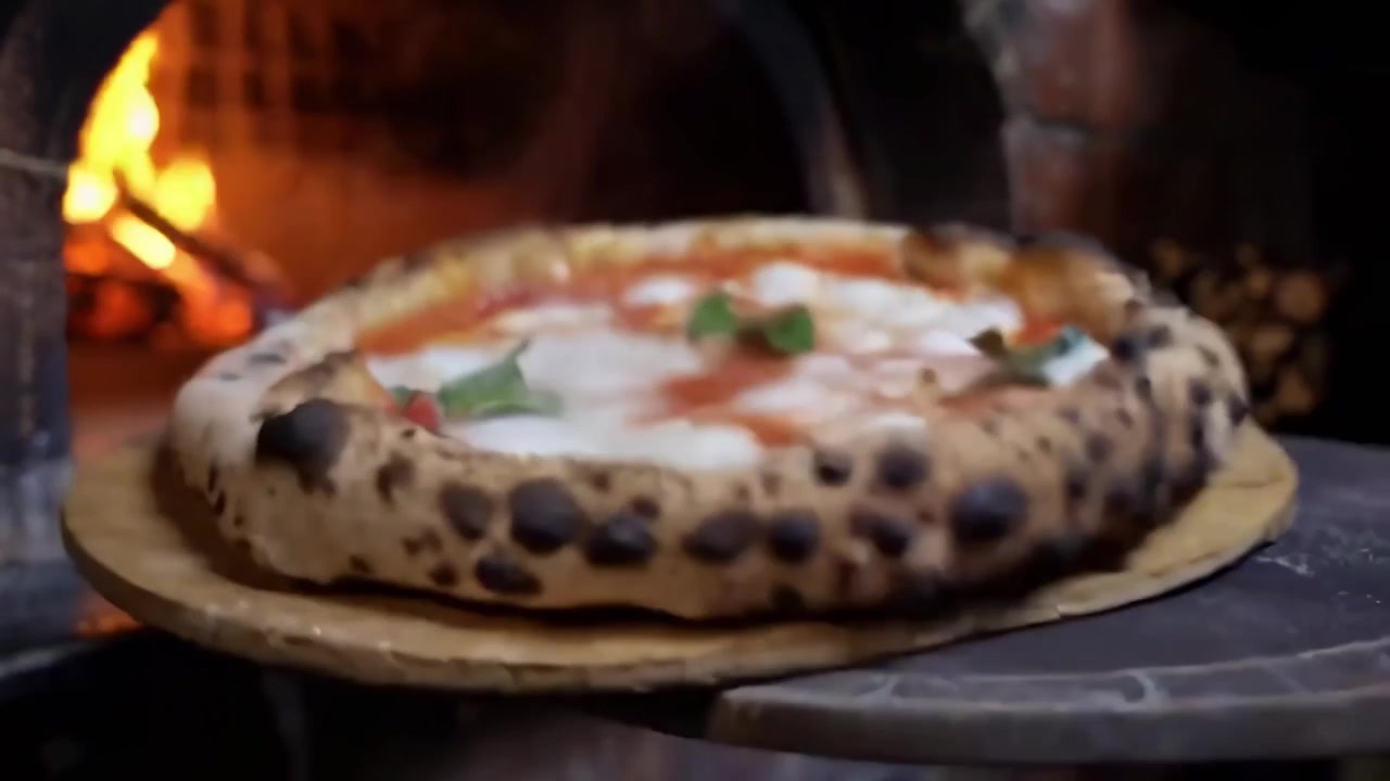 Pizza Margherita recém-assada sendo retirada de um forno a lenha quente
