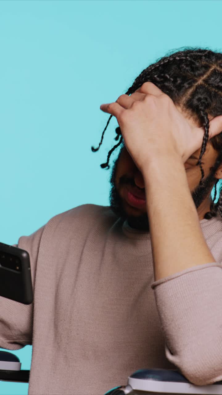 Video verticale. Un uomo in sedia a rotelle si sente triste dopo aver perso a un videogioco sul cellulare