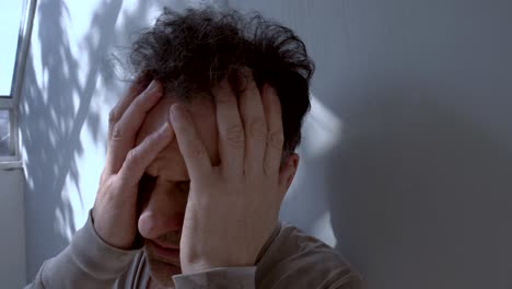 a distressed male with a pensive look holds his face, illustrating a moment of emotional struggle