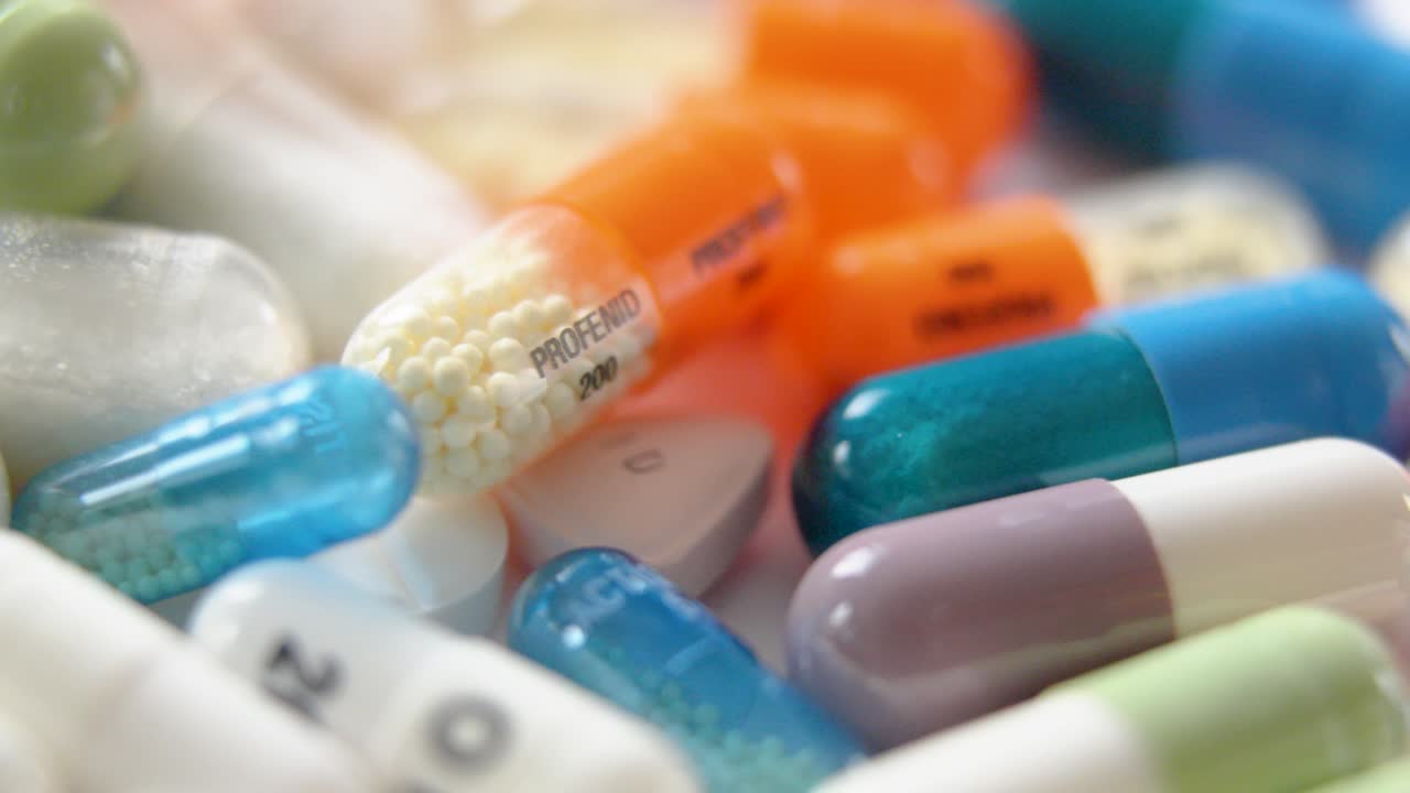 tilting shot of various brands and types of medications out of a bottle
