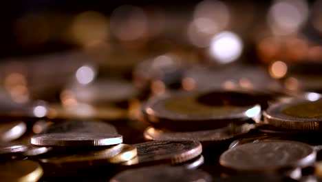 pan shot of close up money coin stacking on  the floor in dark light , business and financial for money saving or the investment background concept  , extremely close up and shallow dof