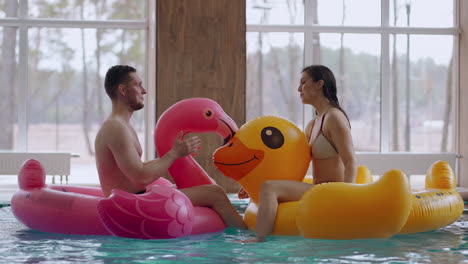 los visitantes felices nadan en divertidos círculos inflables en la piscina del parque acuático, se relajan y se divierten.