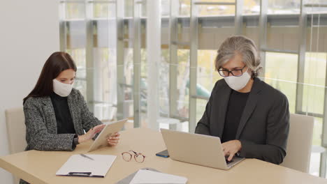 coworkers in masks working at table