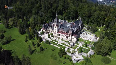 aerial orbit shot around peleș castle near forest in romania on sunny summer day