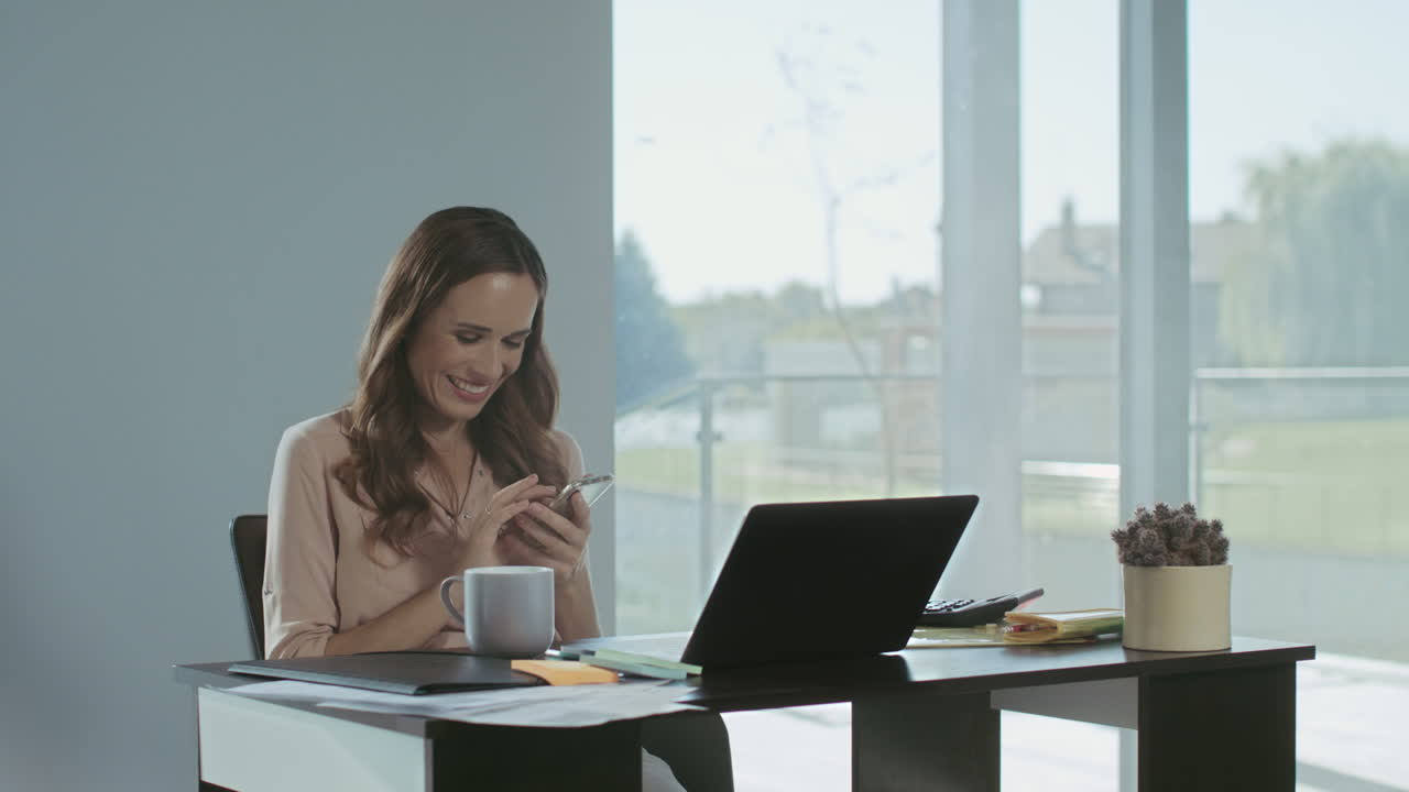 Happy woman looking at phone in luxury house