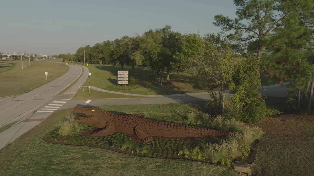 A 4K half orbit aerial view of the new metal alligator sculpture and sign at the entrance to Armand Bayou Nature Center in Pasadena, Texas.