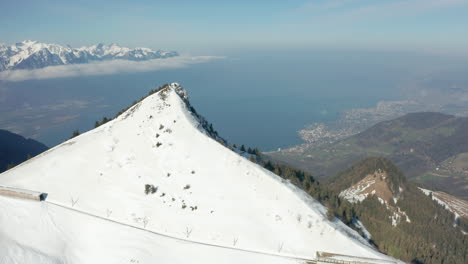 Aerial-reveal-of-beautiful-green-valley-in-a-snow-covered-mountainscape