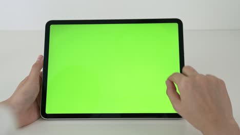 woman holding digital tablet with green screen and touch device browsing internet.