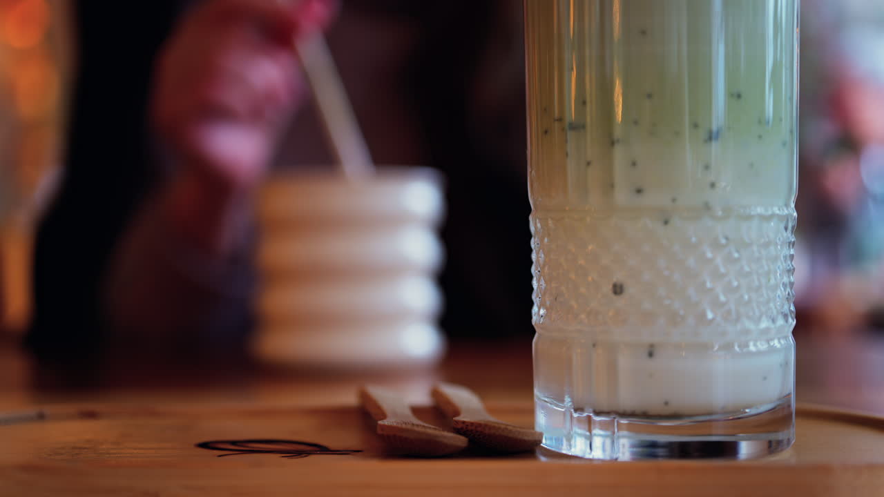 Close up of a matcha latte with a woman drinking at a table at a cafe on the background