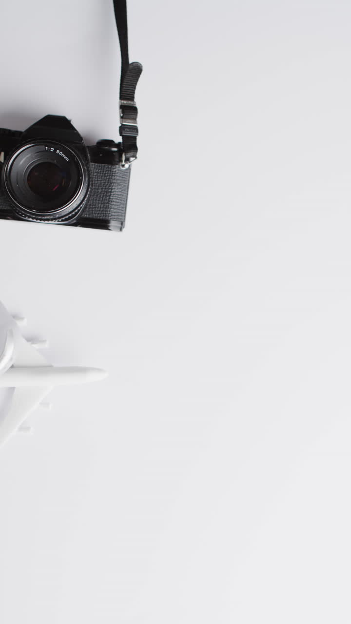 Vertical video of suitcase and camera with copy space on white background