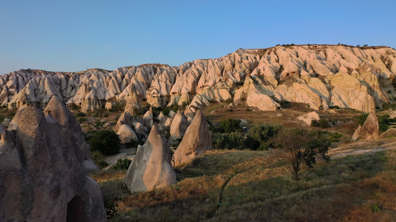 터키 카파도키아의 큰 산을 드러내기 위해 언덕 꼭대기에 서 있는 외로운 남자의 서사시적 공개 영화 드론 샷