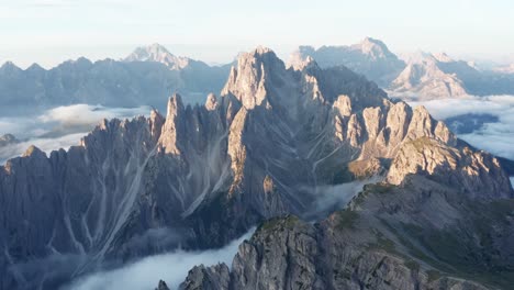 mystic clouds cover in the valley between cadini di misurina mountains during golden sunrise