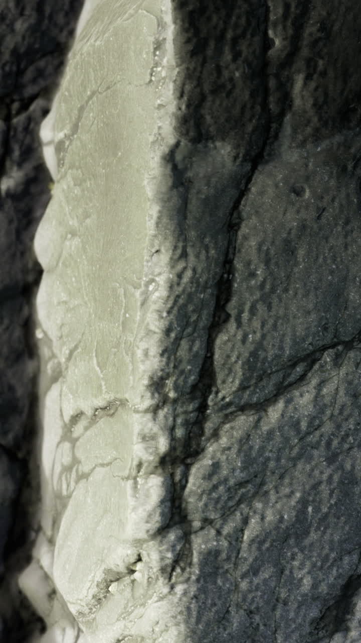 Primo piano di una superficie rocciosa con texture che mostra crepe e dettagli.