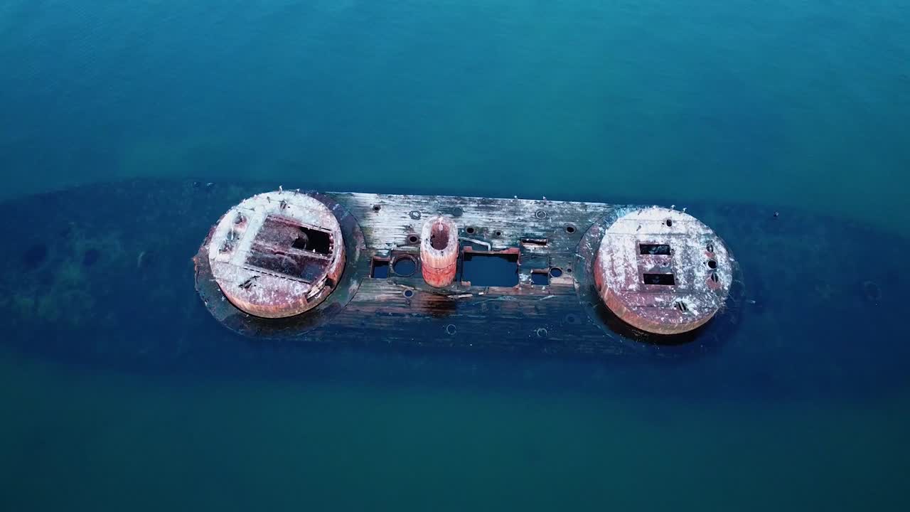 Tilt-up shot from a shipwreck, revealing the rusted hull and scattered debris, with ocean waves crashing around it, capturing a haunting scene of maritime history.