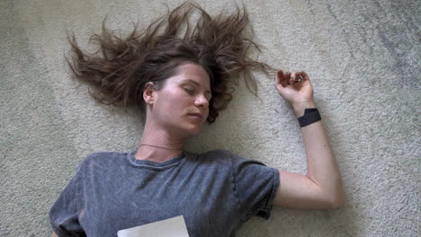 a serene shot of a woman lying on the ground, holding a love letter to her chest with her eyes closed. the camera slowly zooms in while spinning around her, creating a dreamy effect.