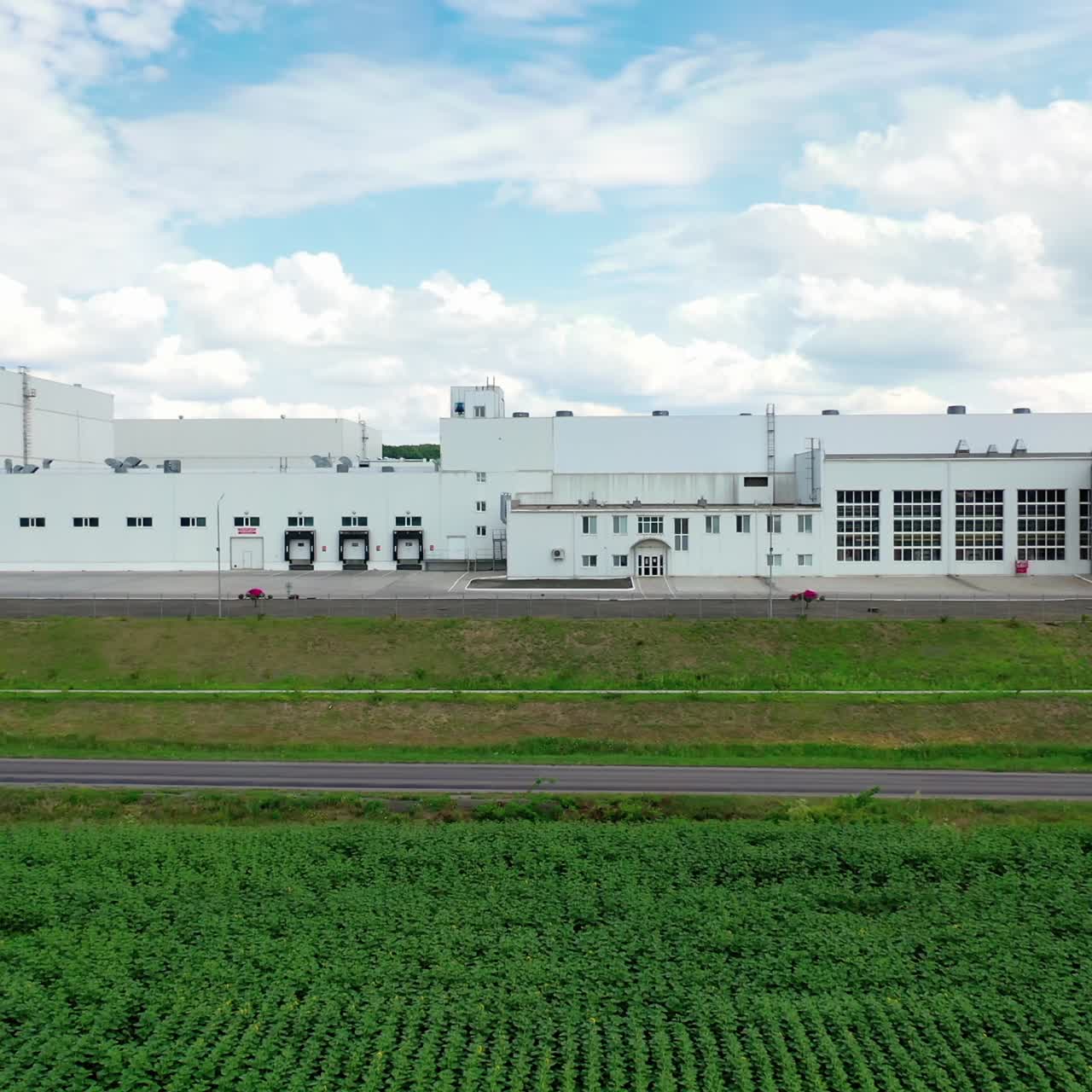 Large innovative plant under the sky. Modern industry with white buildings on field. Front view. Motion camera to the right