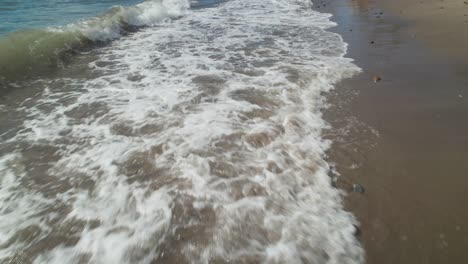 olas del océano en la playa, inclinándose hasta el nivel del horizonte para revelar la costa