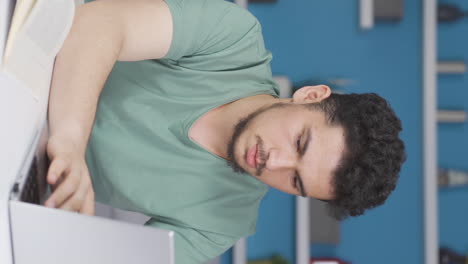 Vertical-video-of-The-male-student-who-finishes-the-homework-is-happy-and-peaceful.