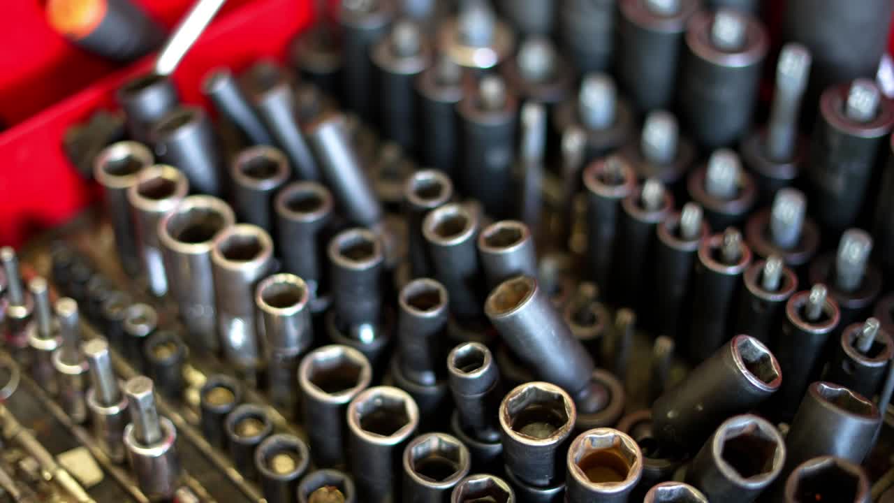 오른쪽에서 왼쪽으로 느린 팬 역학 지저분하고 혼란스러운 빨간색 도구 상자, 많은 소켓 렌치 및 기타 도구가 있는 내부 작업자 홈 비즈니스 차고 상점