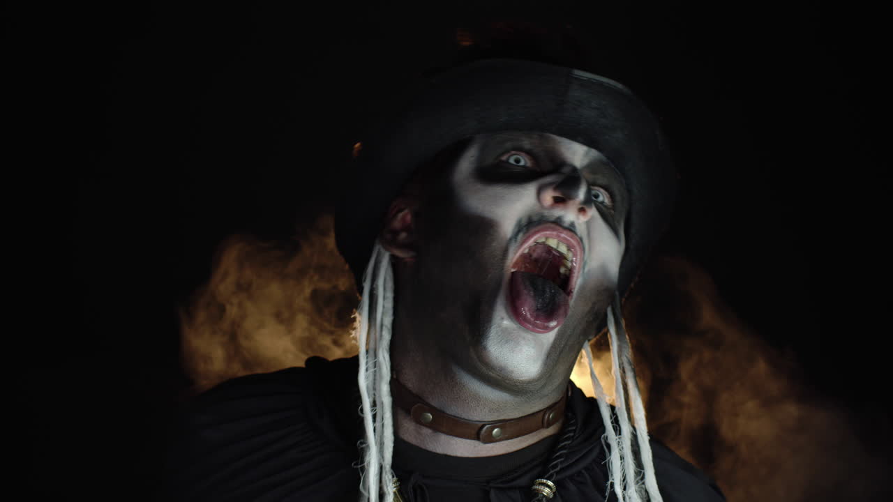 스레이트를 입은 무서운 남자 할로윈 메이크업 화를 내며, 머리를 흔들고, 혀를 보여주는