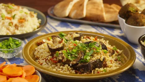 sprinkling greenery on bulgur with eggplant close-up, couscous with meat on background. traditional middle eastern culture. delicious rice with meat. arabian cuisine. homemade food concept