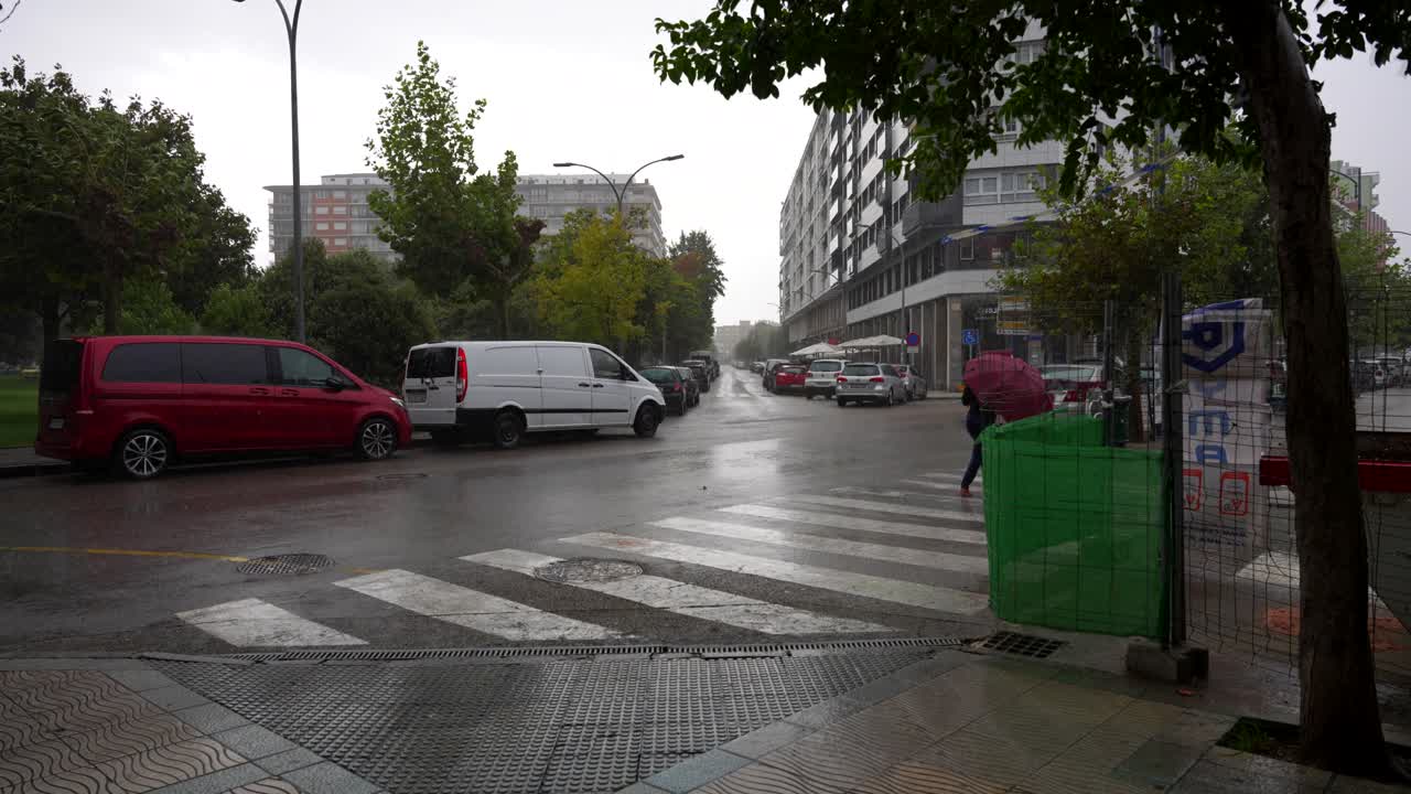 Rainy day in Laredo Cantabria with people walking under umbrellas and wet streets on a windy day