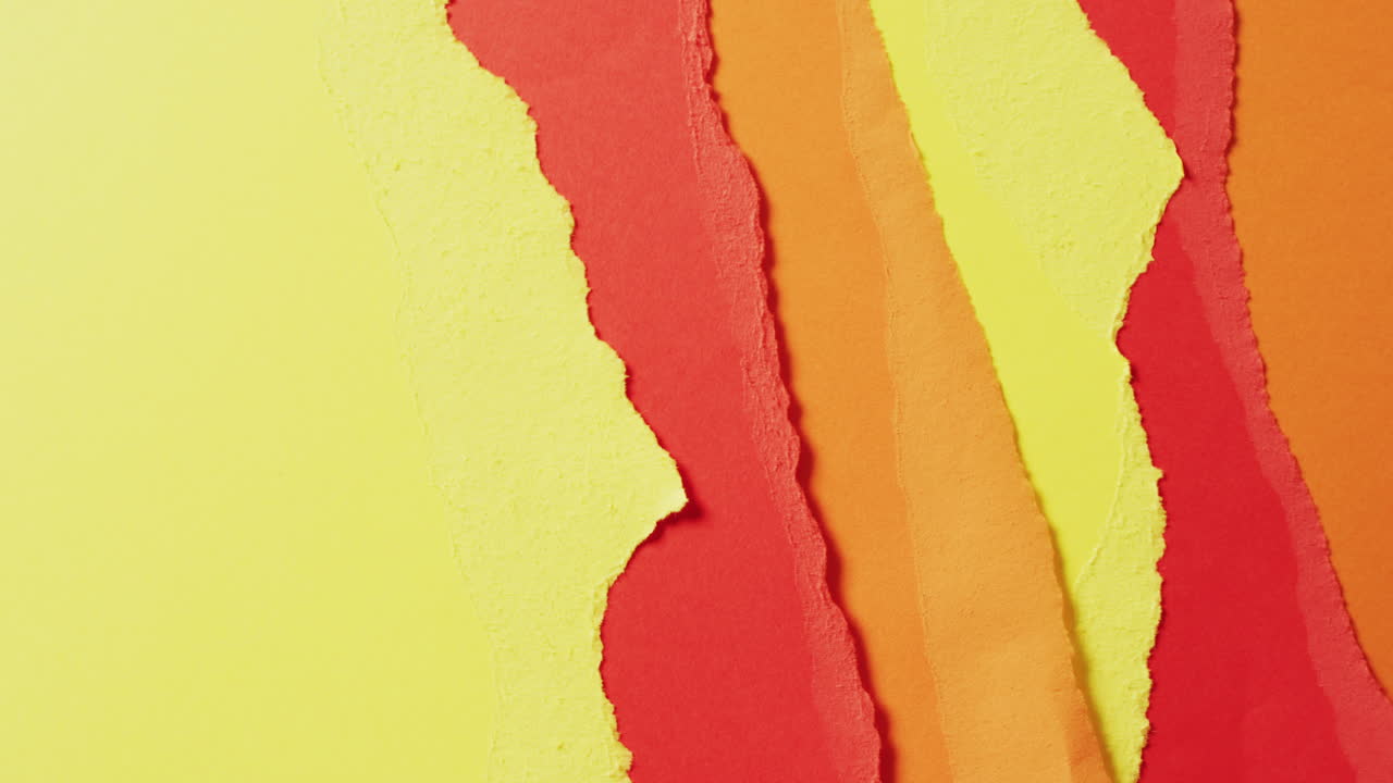 Video of close up of torn pieces of yellow, red and brown paper background