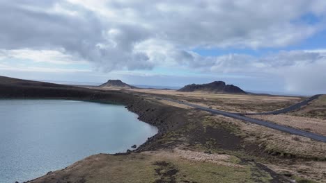 this aerial view of a teal lake in iceland, surrounded by rocky terrain and green grass, is a testament to the country's diverse natural beauty