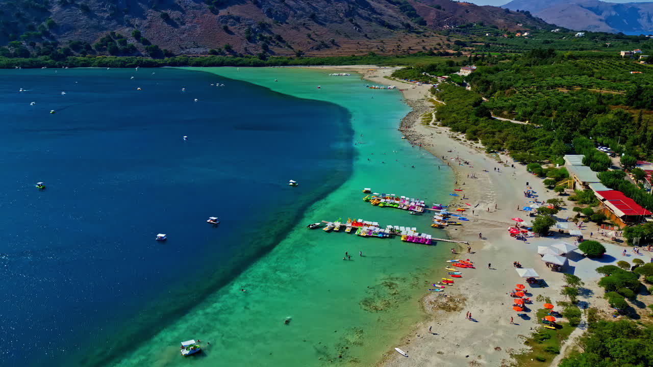 Aerial view of a beautiful lake with turquoise water, sandy beach and people enjoying summer vacation
