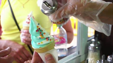 ice cream cones being topped with sprinkles