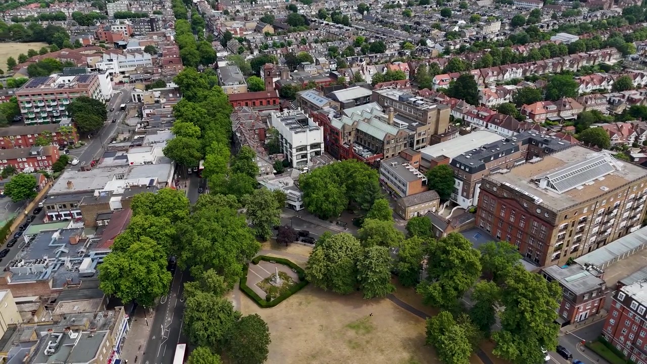 Edifici del centro città, negozi e uffici sorgono accanto a un'area verde ingiallita dalla siccità con alberi maturi e strade trafficate