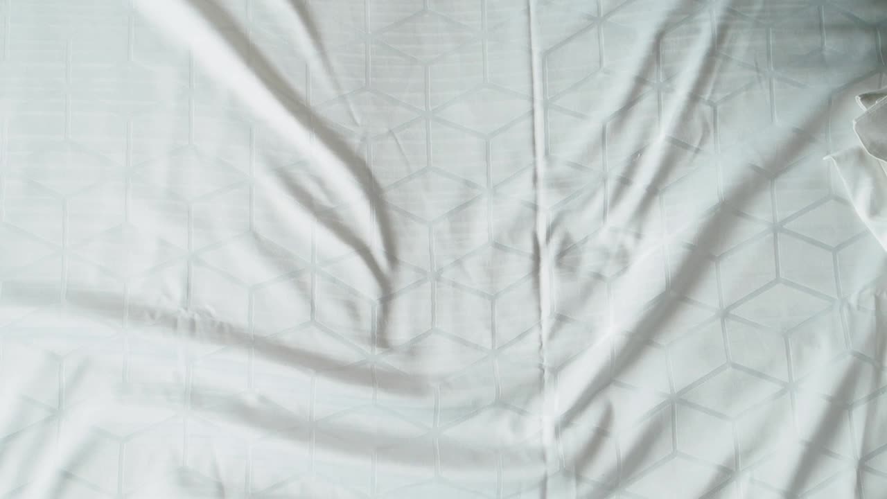 человек, делающий постель с белыми рисунками.