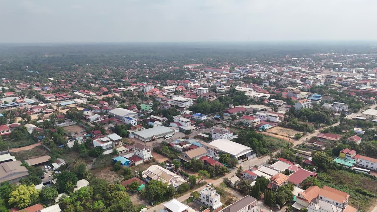 Aerial view of Krong Siem Reap, Cambodia. The cityscape is by a dense collection of low to medium-rise buildings, primarily residential, with a variety of roof colors including red, blue, and white.