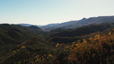 Beautiful-mountain-landscape,-with-mountain-peaks-covered-with-golden-forest,-push-in-drone-shot