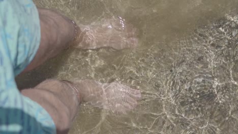 bird's eye view of a man's feet in clear water on the beach