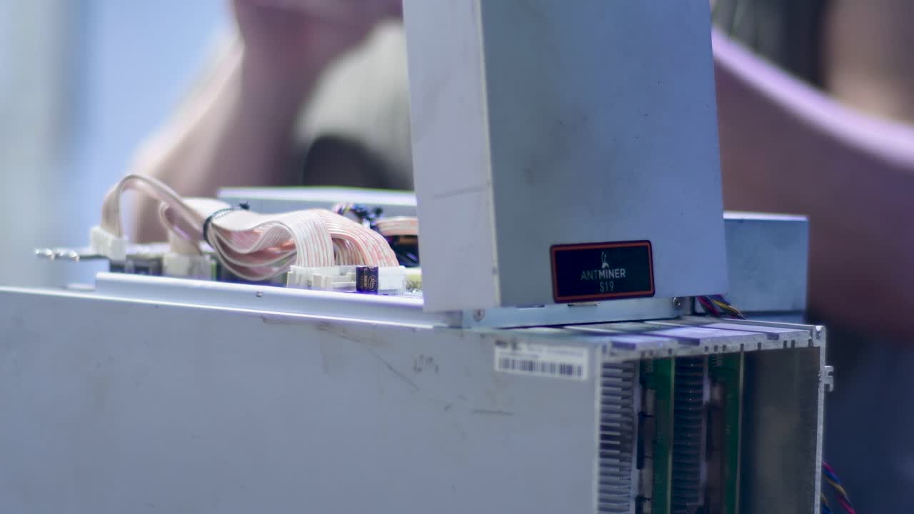 Close-up view of the complex internal structure and ribbon cables of a high-power ASIC miner being repaired