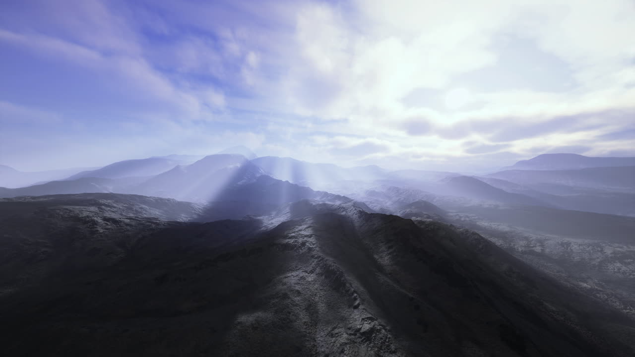 Sunlight breaks through clouds over majestic mountain landscape at dawn