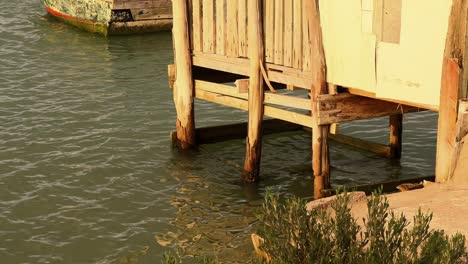 capturando imágenes fijas de una escena frente al mar mientras la cámara captura la inmersión gradual de los cimientos de una casa de madera en las aguas tranquilas de abajo