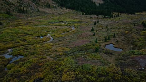 drone footage of a mountain road cutting through rolling hills and valleys, with a lake in the background