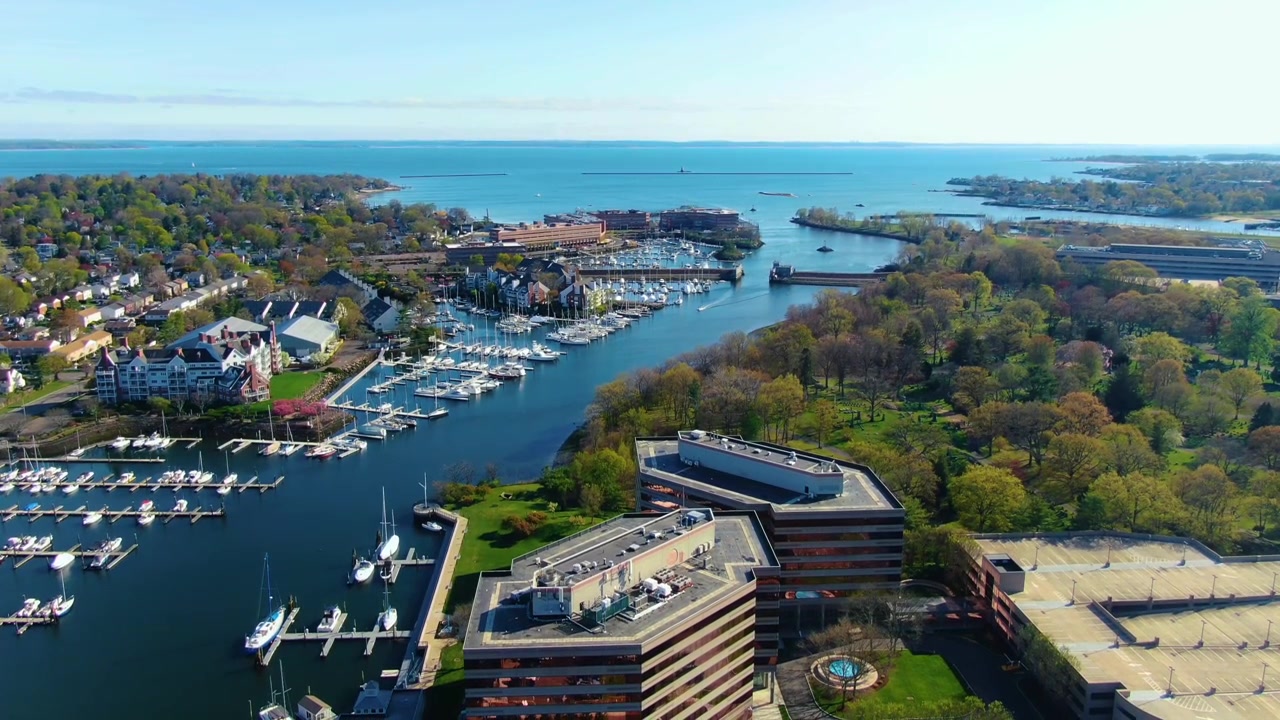 Veduta aerea statica di un porto turistico circondato da case sul lungomare, alberi e acque costiere durante una giornata primaverile a Stamford, Connecticut