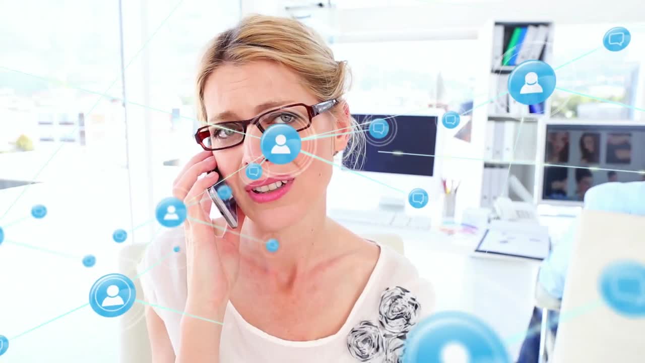 Animation of connected icons over confused caucasian woman talking on smartphone at office