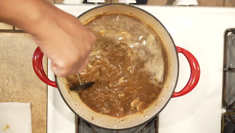 stirring wild rice mushroom soup as it boils in a pot on the stove in slow motion - overhead view wild rice series