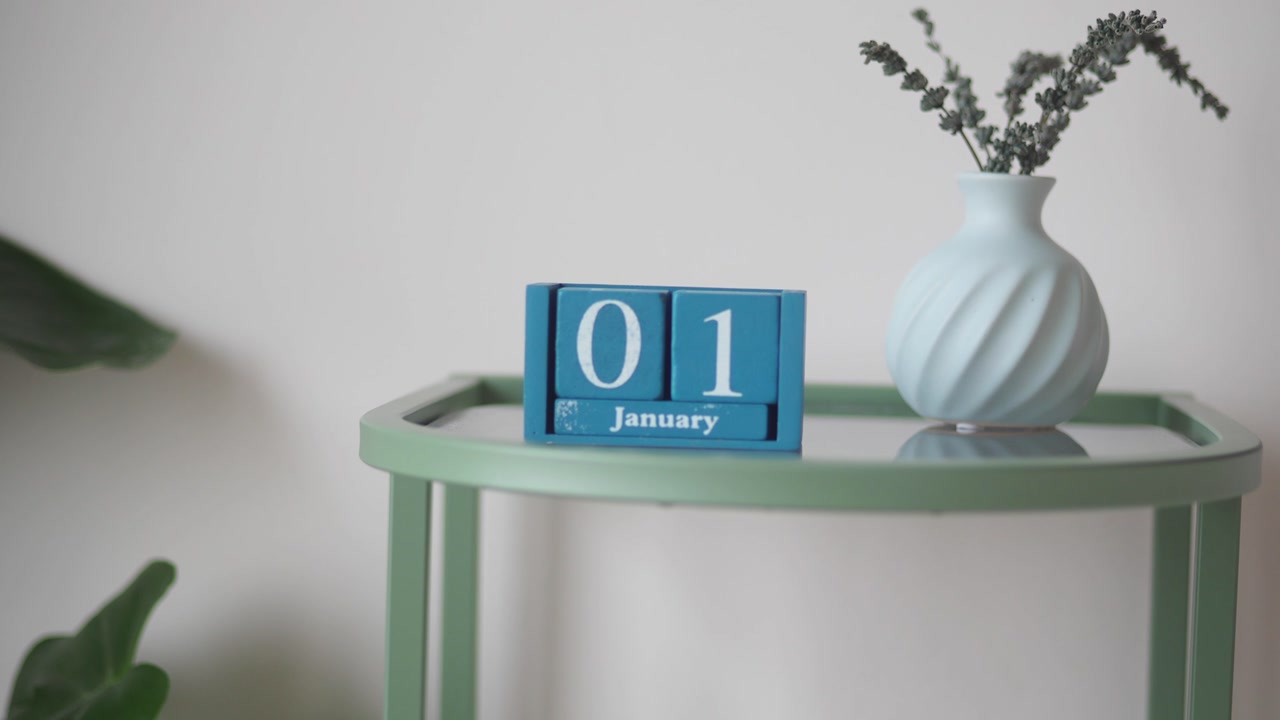 Blue Wooden Block Calendar Showing January 1st with Vase on Side Table