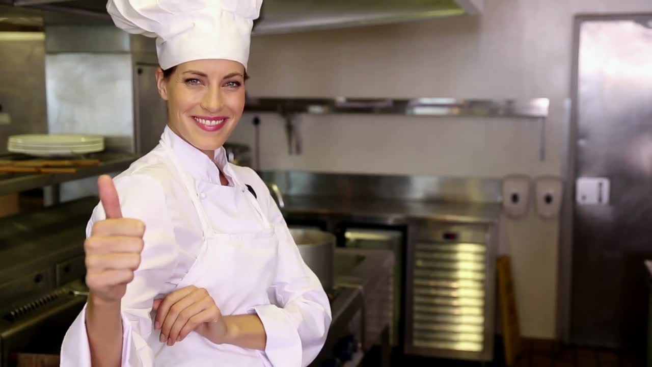 Bella chef che sorride alla telecamera e fa il pollice in su
