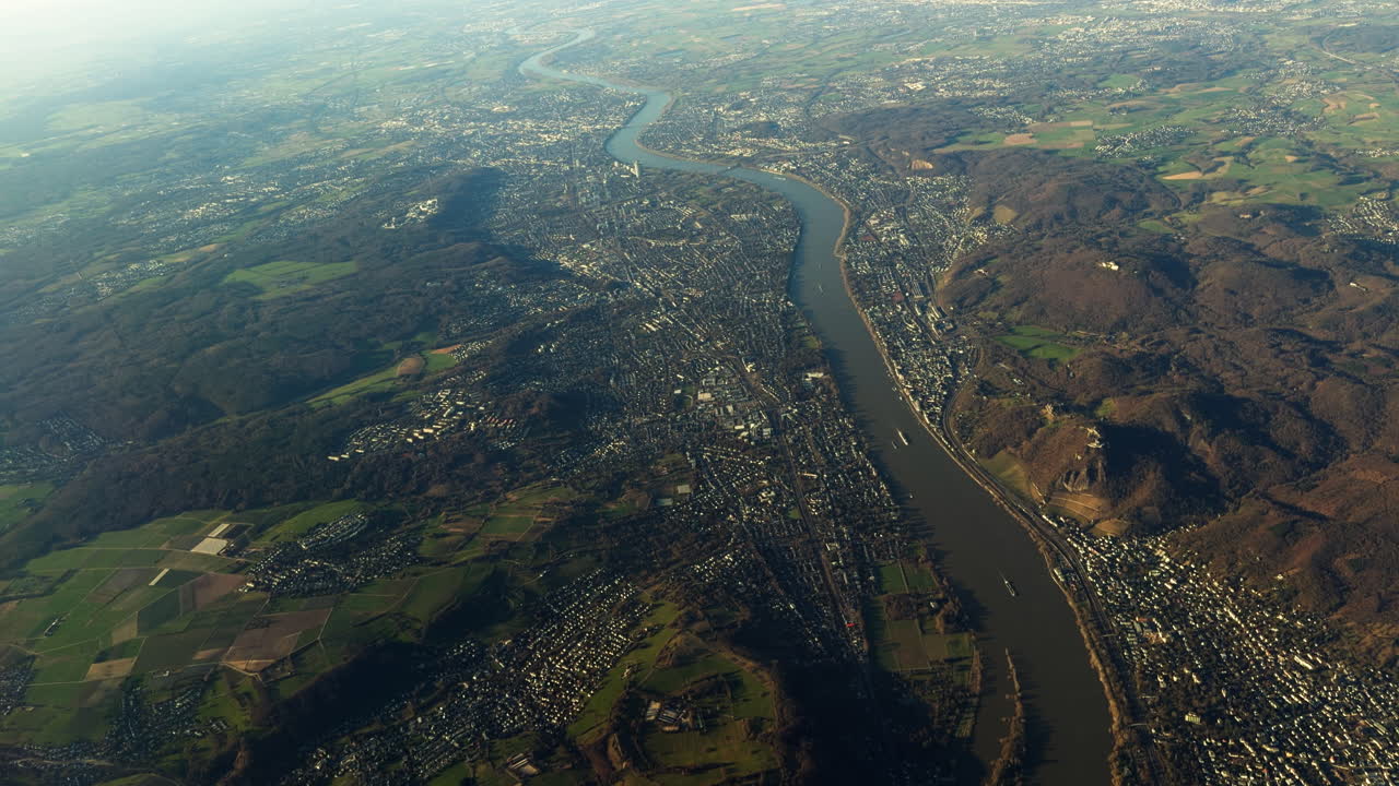 Vista aerea del fiume Reno che scorre attraverso città e campagna vicino a Colonia, Germania. Paesaggio che mostra aree urbane, terreni agricoli e colline lungo una delle principali vie navigabili d'Europa